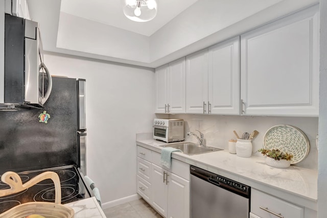 kitchen with appliances with stainless steel finishes, a sink, white cabinets, and light countertops