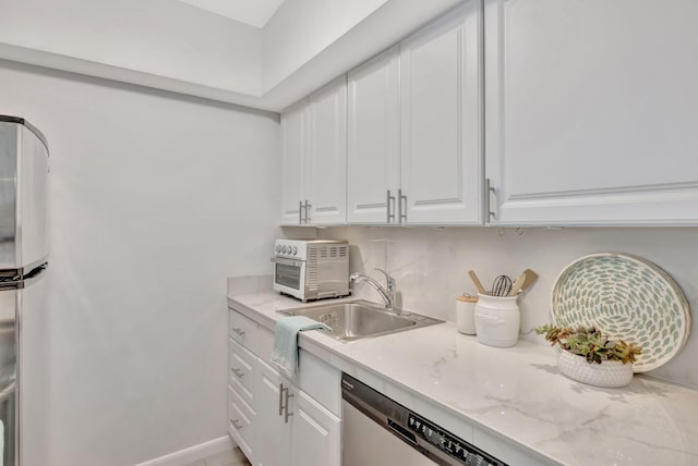 kitchen with a sink, white cabinetry, decorative backsplash, and light stone counters