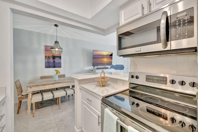 kitchen featuring appliances with stainless steel finishes, white cabinetry, hanging light fixtures, and light tile patterned flooring