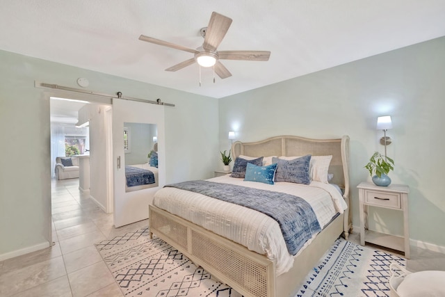 bedroom featuring baseboards, a barn door, light tile patterned floors, and a ceiling fan