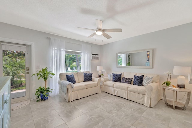 living room with a ceiling fan, light tile patterned floors, a wall mounted air conditioner, and a textured ceiling