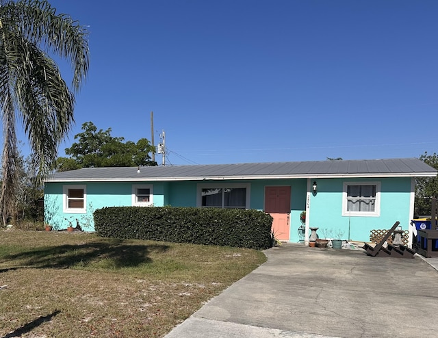 2804 NE Hickory Ridge Ave, Jensen Beach, FL 34957 - single story home with a front lawn, stucco siding, and metal roof