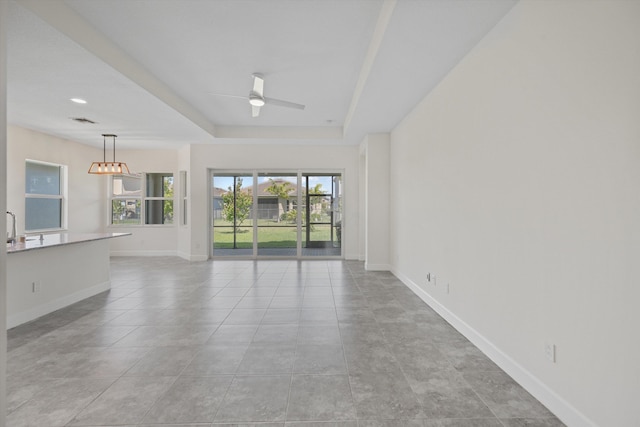 4641 Woodland Way, Westlake, FL 33470 - unfurnished living room with ceiling fan, baseboards, a sink, a tray ceiling, and light tile patterned floors