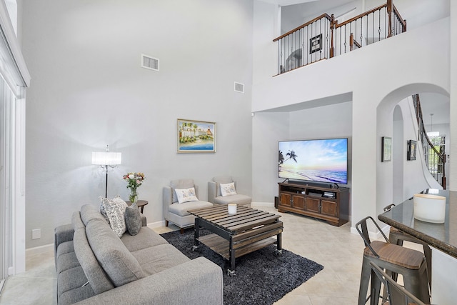 12341 NW 78th Mnr, Parkland, FL 33076 - living room with arched walkways, a towering ceiling, light tile patterned flooring, baseboards, and stairs