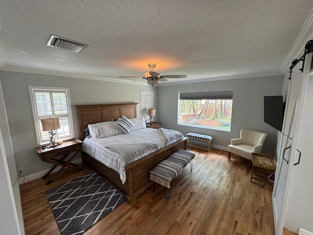 14324 Paddock Dr, Wellington, FL 33414 - bedroom with a barn door, a textured ceiling, wood finished floors, crown molding, and multiple windows