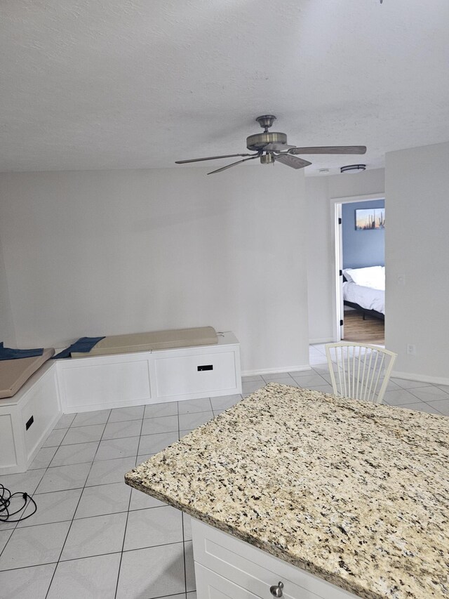 389 SE Whitmore Dr, Port Saint Lucie, FL 34984 - kitchen featuring light tile patterned floors, white cabinetry, ceiling fan, and light stone counters