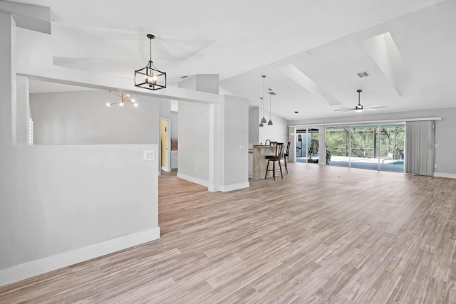 139 NE Royce Ave, Port Saint Lucie, FL 34983 - unfurnished living room featuring baseboards, vaulted ceiling, light wood-style flooring, a chandelier, and a ceiling fan