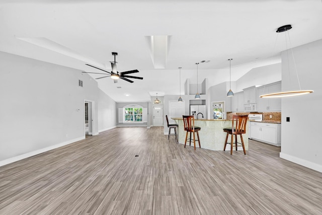 139 NE Royce Ave, Port Saint Lucie, FL 34983 - living room featuring vaulted ceiling, a ceiling fan, baseboards, and light wood finished floors