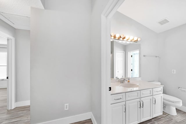 139 NE Royce Ave, Port Saint Lucie, FL 34983 - bathroom featuring wood finished floors, toilet, vanity, and baseboards