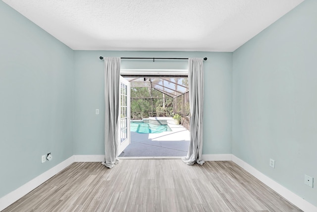 139 NE Royce Ave, Port Saint Lucie, FL 34983 - empty room with wood finished floors, baseboards, a sunroom, and a textured ceiling
