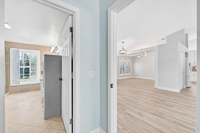 139 NE Royce Ave, Port Saint Lucie, FL 34983 - hall with plenty of natural light, a chandelier, baseboards, light wood-style flooring, and a textured ceiling