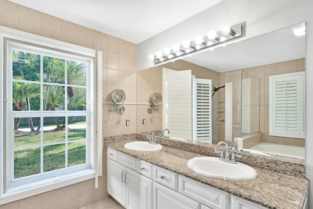 139 NE Royce Ave, Port Saint Lucie, FL 34983 - bathroom featuring plenty of natural light, a tile shower, double vanity, tile patterned floors, and tile walls