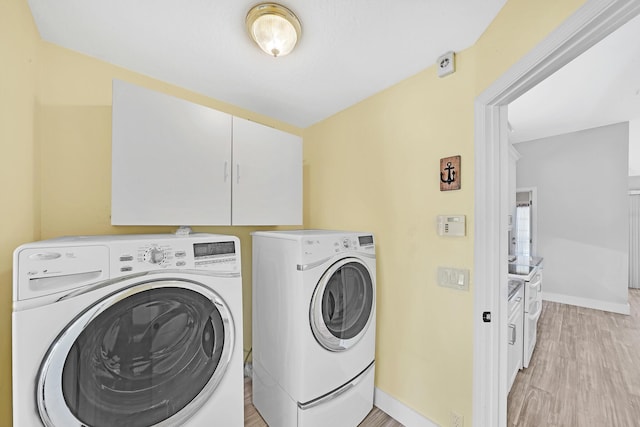 139 NE Royce Ave, Port Saint Lucie, FL 34983 - laundry room featuring washer and dryer, baseboards, light wood finished floors, and cabinet space