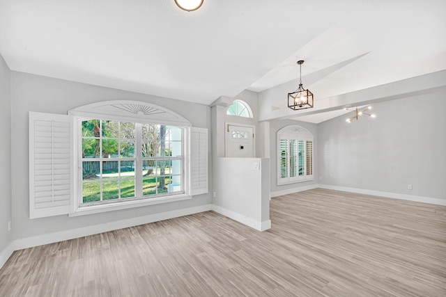 139 NE Royce Ave, Port Saint Lucie, FL 34983 - unfurnished living room featuring a chandelier, baseboards, lofted ceiling, and light wood-style floors