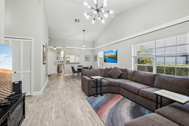 living room with a chandelier, light wood-type flooring, high vaulted ceiling, and baseboards