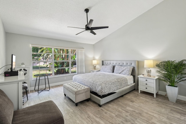 bedroom featuring light wood-type flooring, baseboards, a ceiling fan, vaulted ceiling, and a textured ceiling