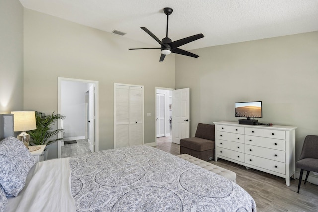 bedroom with high vaulted ceiling, wood finished floors, ensuite bathroom, a ceiling fan, and baseboards
