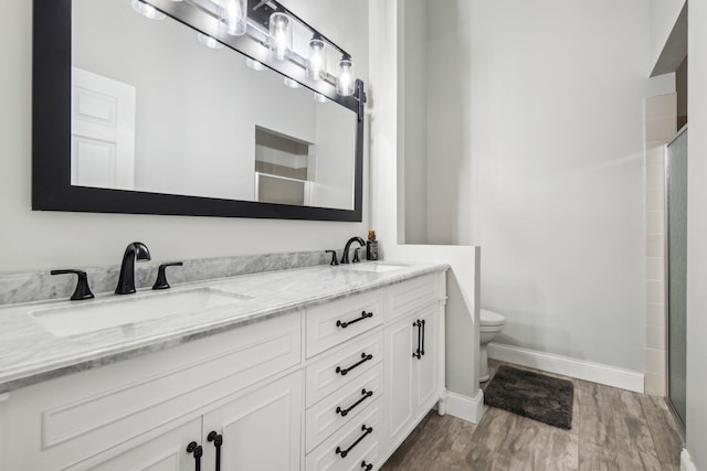 full bath featuring wood finished floors, baseboards, toilet, double vanity, and a shower