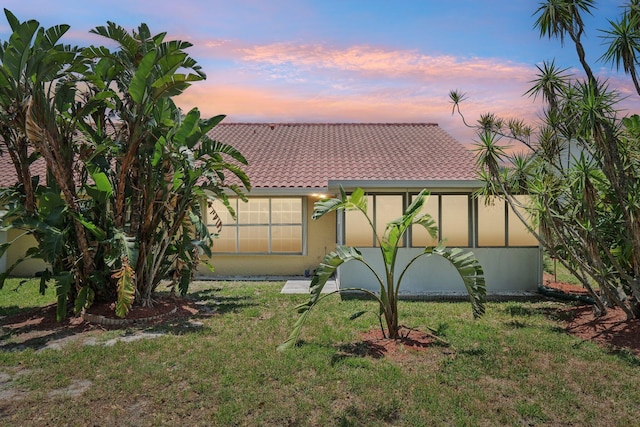 view of front of house featuring a tiled roof, a yard, and stucco siding