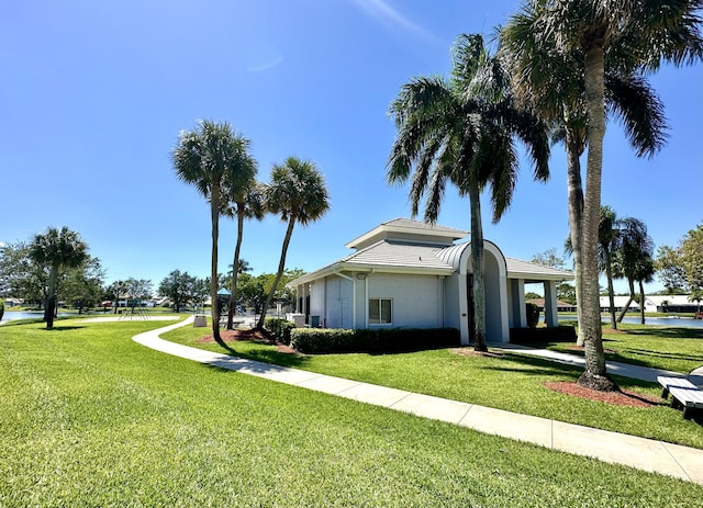 view of side of property with a lawn, stucco siding, and a water view