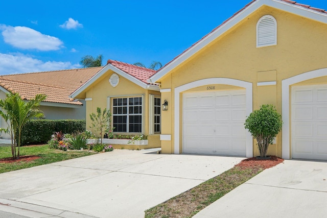 view of front of house with stucco siding, concrete driveway, and a tiled roof