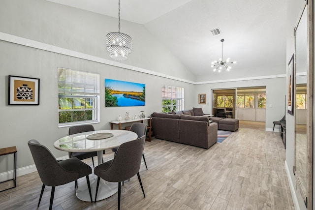 dining space with a chandelier, light wood-style floors, high vaulted ceiling, and baseboards