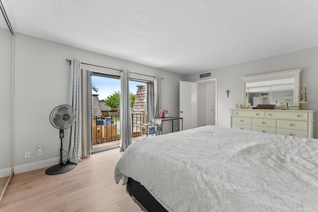 bedroom with access to exterior, light wood-style flooring, baseboards, and a textured ceiling