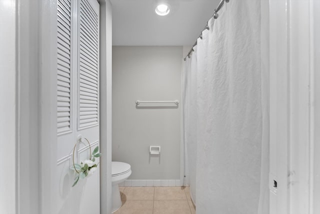 bathroom featuring toilet, tile patterned floors, and baseboards