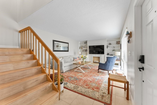 living room featuring stairs, tile patterned floors, a textured ceiling, and a fireplace