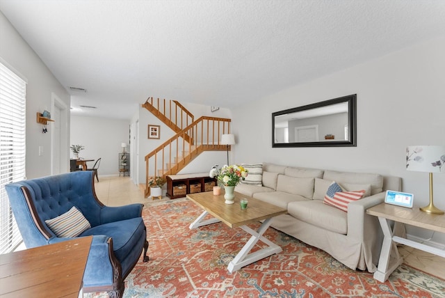 living room with stairway, tile patterned floors, a textured ceiling, and baseboards