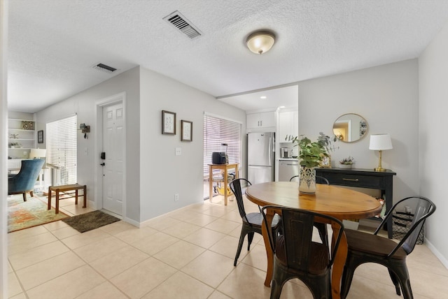 dining space with plenty of natural light, a textured ceiling, baseboards, and light tile patterned floors