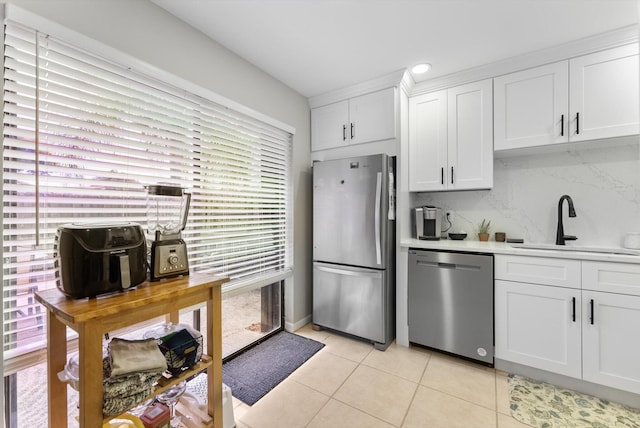 kitchen featuring appliances with stainless steel finishes, decorative backsplash, light tile patterned floors, white cabinetry, and light countertops