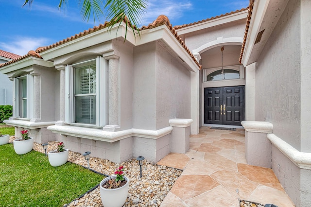 property entrance featuring stucco siding and a tiled roof