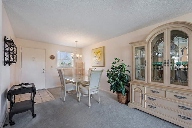 dining area with a chandelier, light colored carpet, a textured ceiling, and baseboards