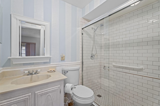 full bath with a shower stall, wainscoting, toilet, and vanity