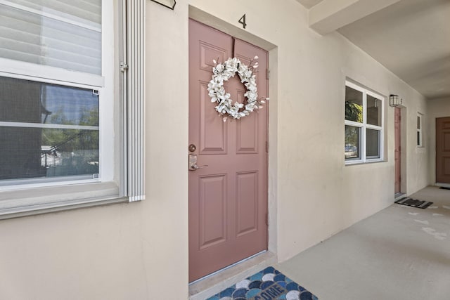 doorway to property with stucco siding and covered porch