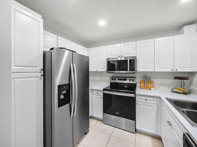 4167 Crystal Lake Dr, Deerfield Beach, FL 33064 - kitchen with stainless steel appliances, light tile patterned floors, white cabinets, a sink, and light countertops