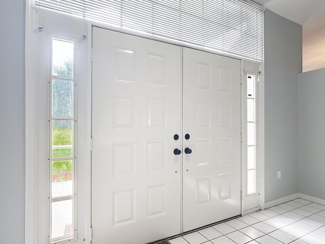 foyer entrance with light tile patterned floors and baseboards