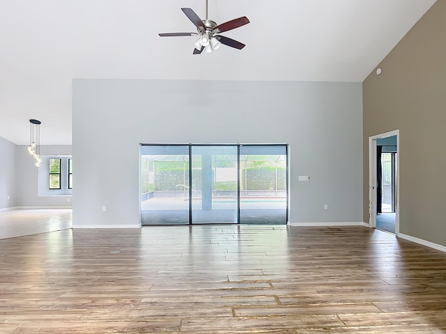 unfurnished room featuring high vaulted ceiling, ceiling fan, wood finished floors, and baseboards