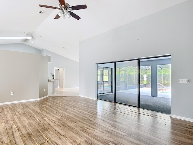 empty room with a ceiling fan, high vaulted ceiling, healthy amount of natural light, light wood-style flooring, and baseboards