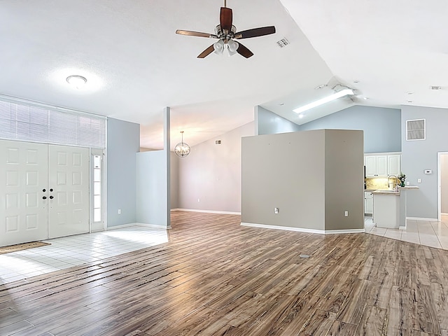 foyer featuring a ceiling fan, light wood-style flooring, lofted ceiling, and baseboards