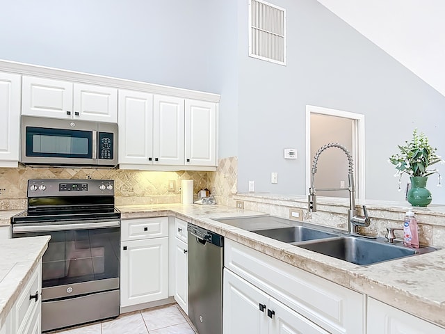 kitchen featuring stainless steel appliances, a sink, light countertops, white cabinetry, and a high ceiling