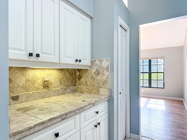 kitchen with light countertops, decorative backsplash, white cabinets, and baseboards
