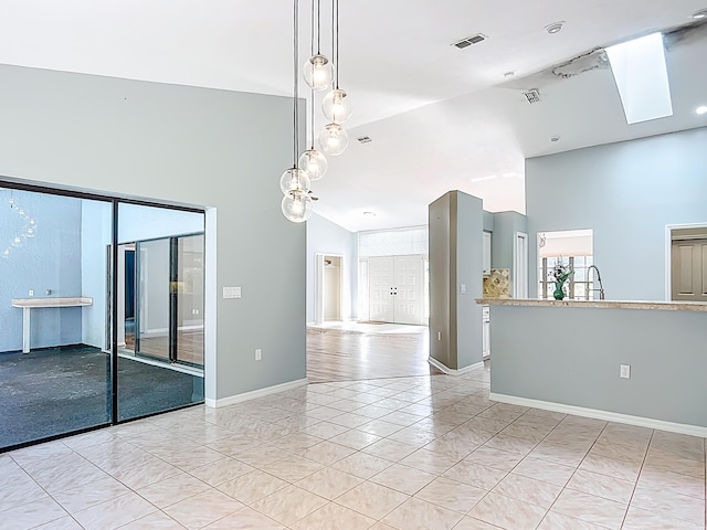 spare room featuring high vaulted ceiling, baseboards, a skylight, and light tile patterned flooring