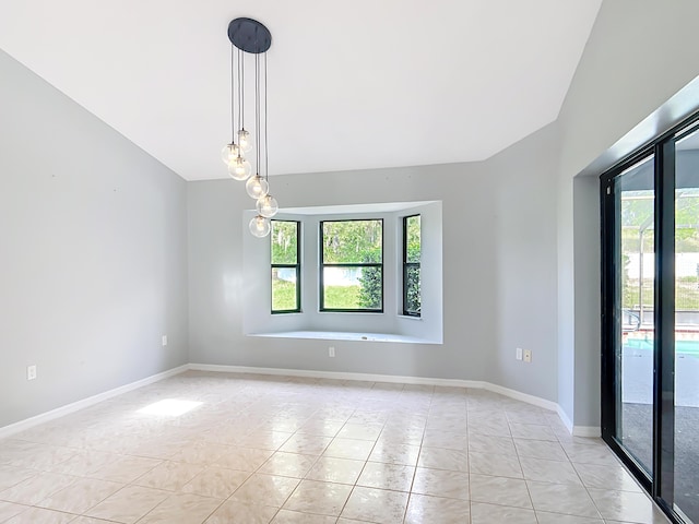 spare room with healthy amount of natural light, lofted ceiling, light tile patterned flooring, and baseboards