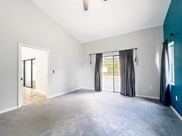 carpeted spare room featuring high vaulted ceiling, a ceiling fan, and baseboards