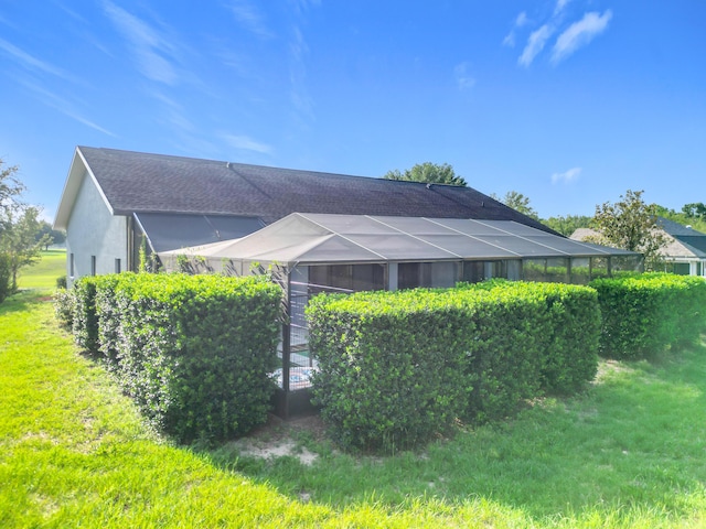 back of property with roof with shingles, stucco siding, and a yard