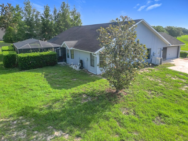 view of side of home featuring an attached garage, a lawn, concrete driveway, and a lanai