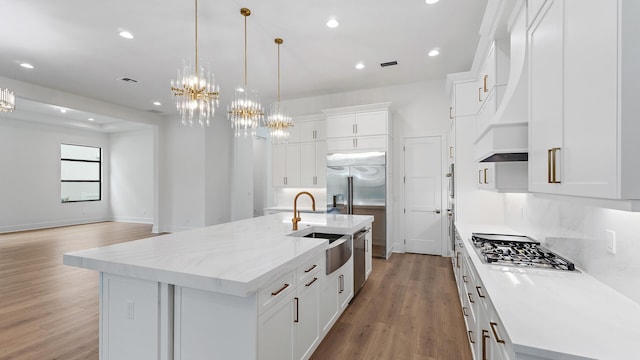 13250 Artisan Cir, Palm Beach Gardens, FL 33418 - kitchen with appliances with stainless steel finishes, a chandelier, light wood finished floors, an island with sink, and recessed lighting