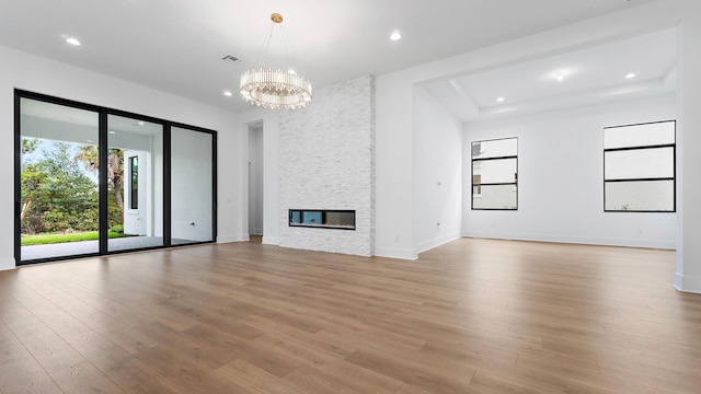 13250 Artisan Cir, Palm Beach Gardens, FL 33418 - unfurnished living room with recessed lighting, a chandelier, light wood-style flooring, and a stone fireplace